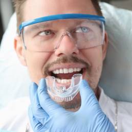 Dentist trying on mouthguard for man patient.